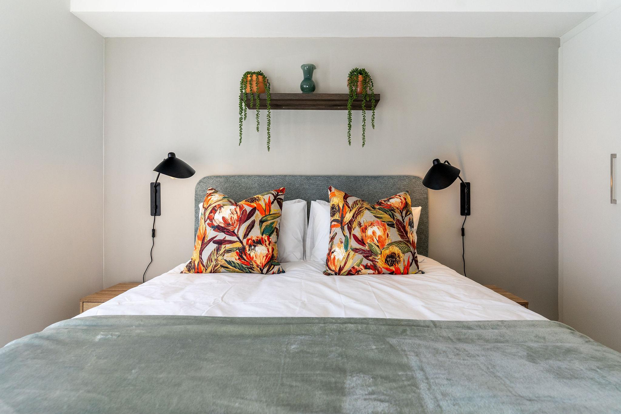 Cape Vine bedroom headboard with reading lamps and floral cushions