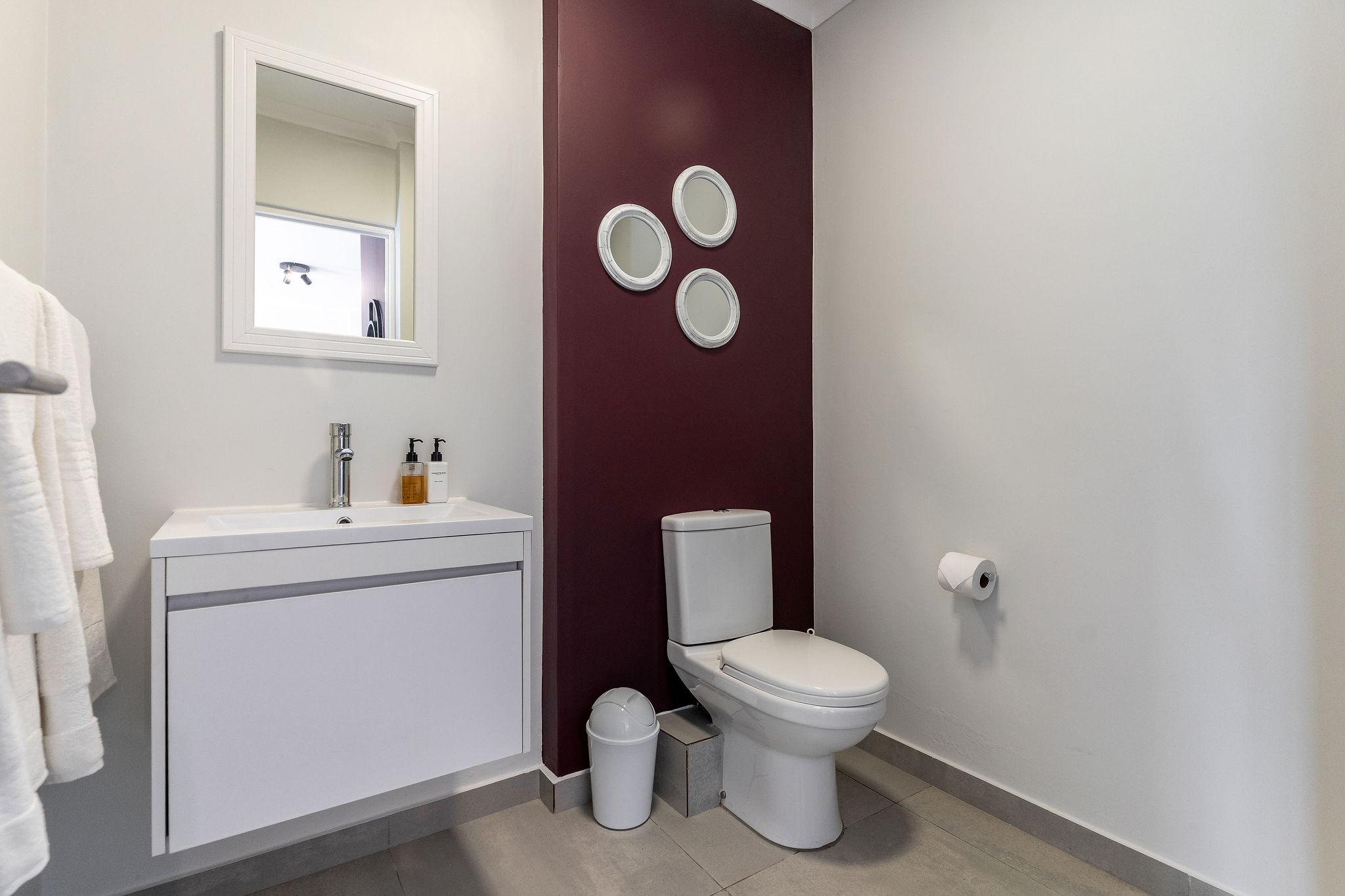 Cape Vine bathroom with feature wall and round mirrors