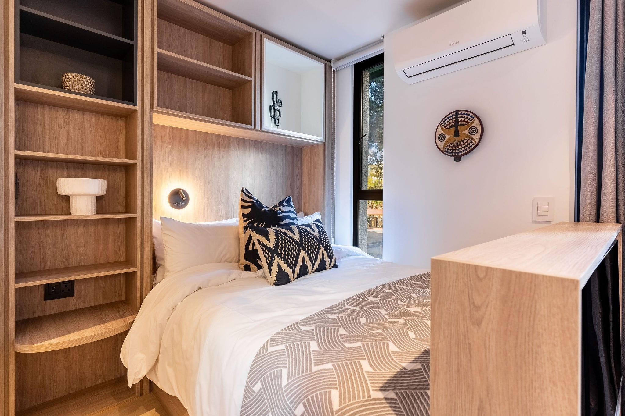 Centrepark bed nook with built-in wooden shelving and patterned scatter cushions