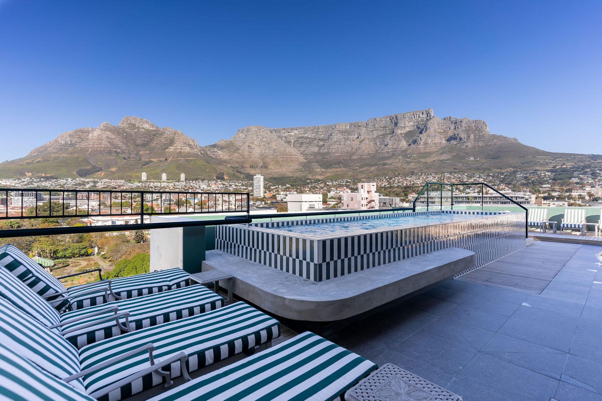 Ten on V rooftop pool with striped sun loungers and a panoramic Table Mountain view