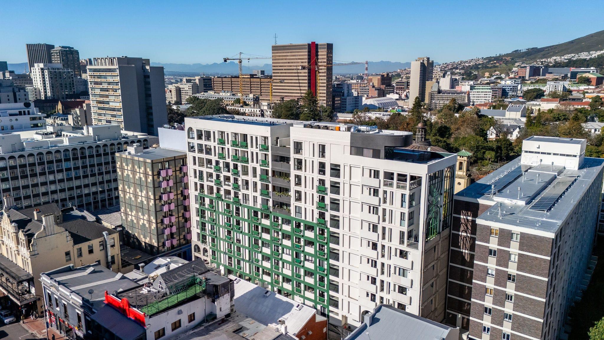 Aerial view of the Ten on V building with its green balcony grid facade and rooftop pool