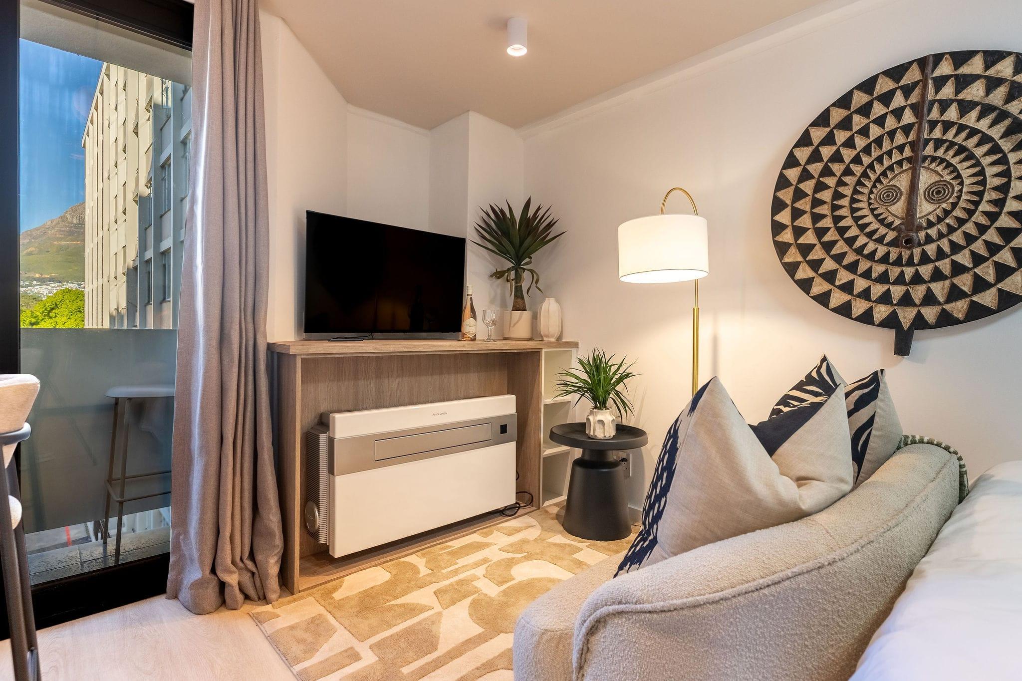 Mountainview lounge corner with wall-mounted TV and floor lamp below an African mask